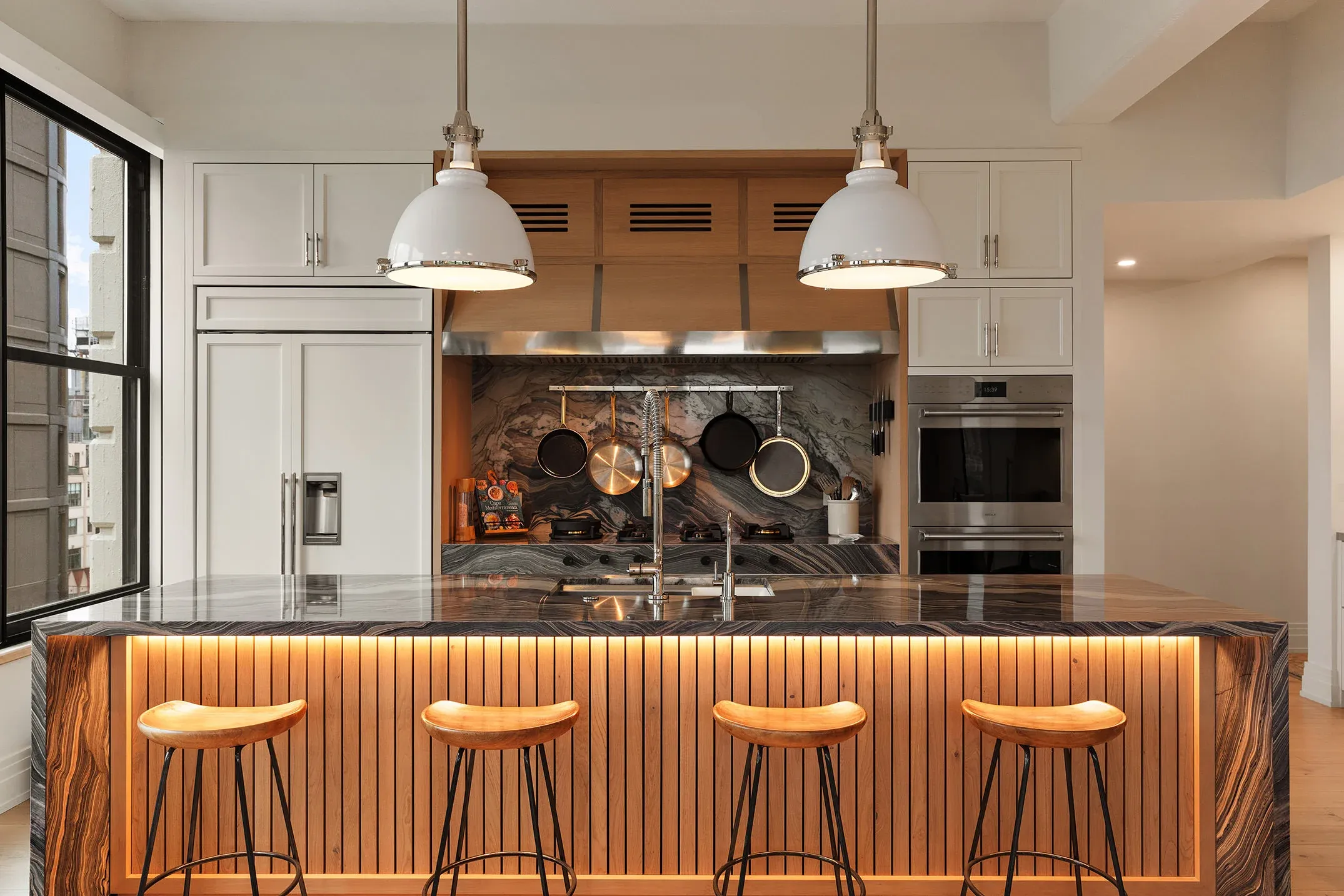 A renovated Brooklyn kitchen with a waterfall marble island and warm under-counter lighting