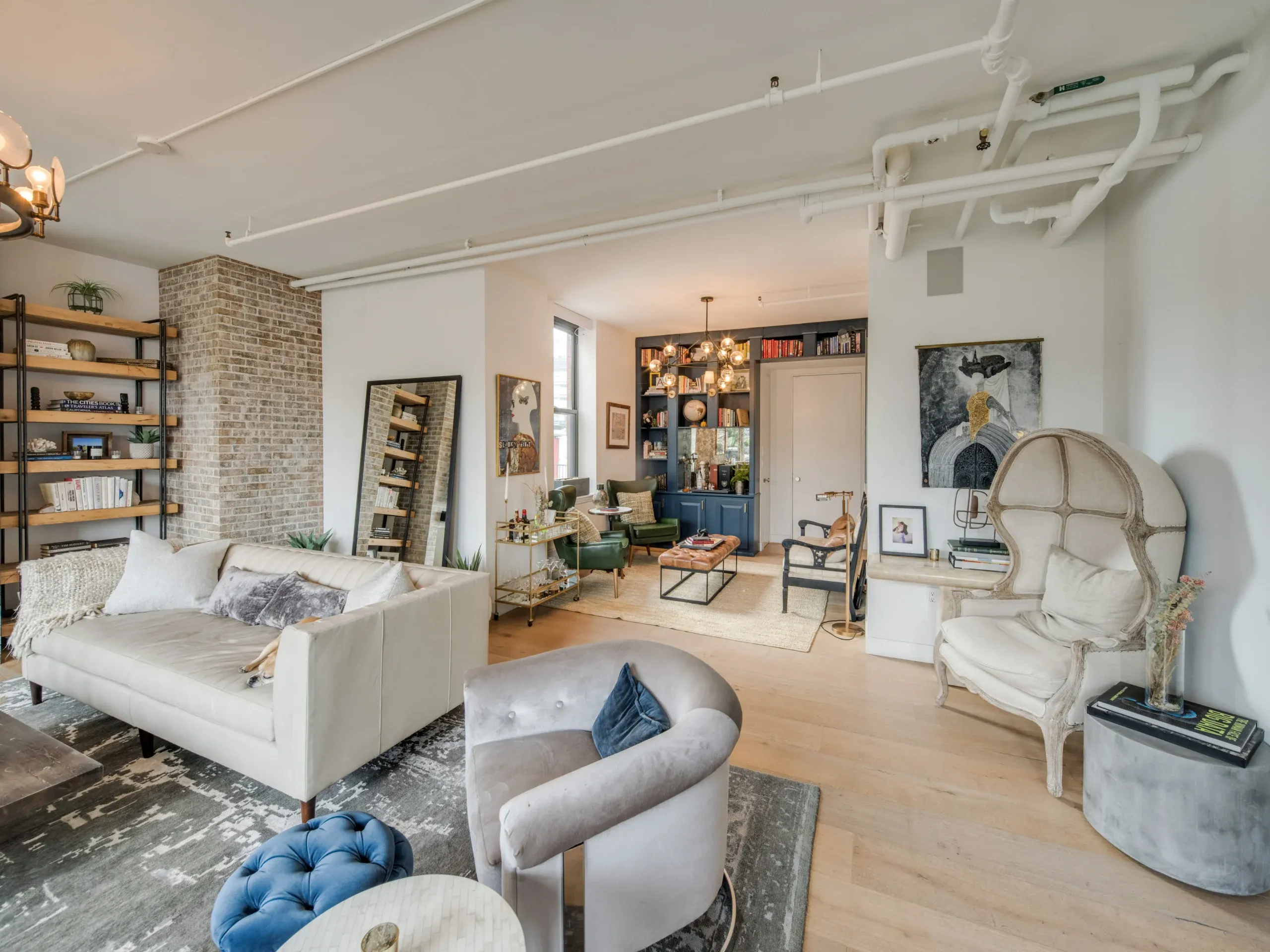A bright loft living room with exposed brick, tall windows and mixed seating