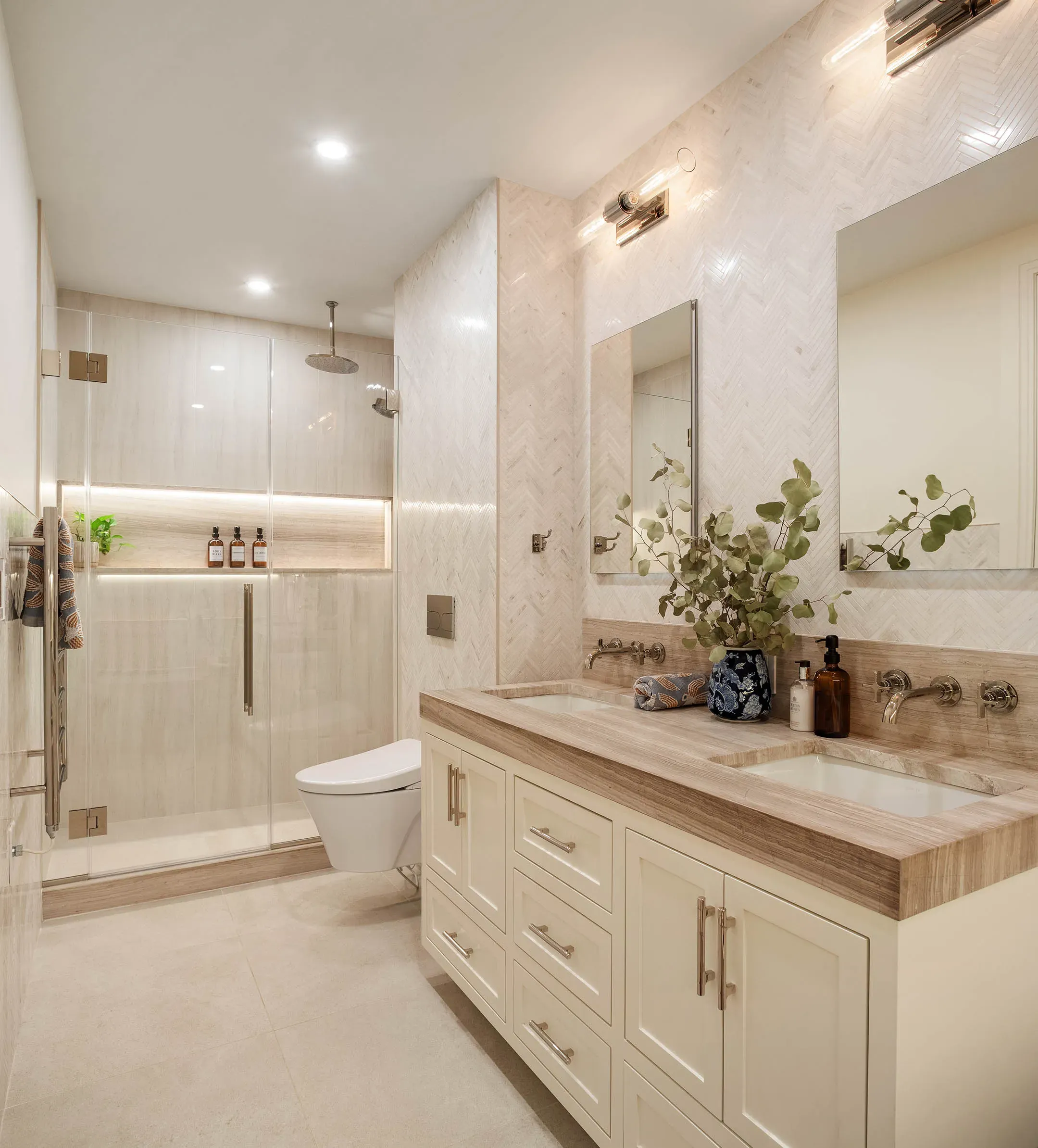 A calm bathroom with a floating vanity, limestone tile and a glass shower