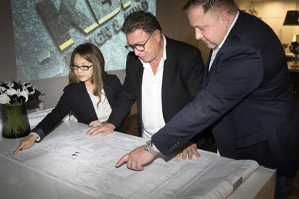 Three members of the KBR team reviewing construction drawings at a table in the showroom
