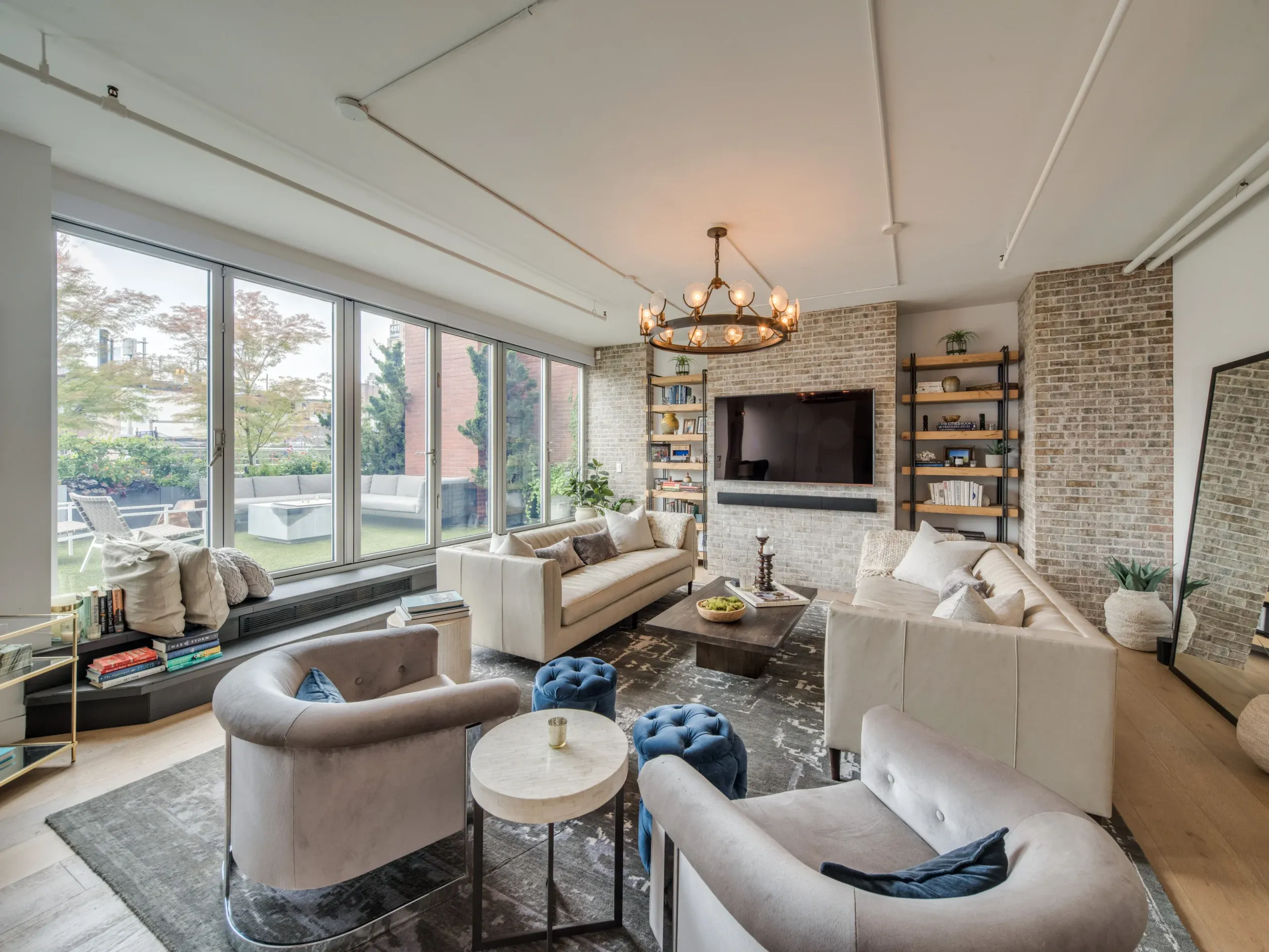 A loft living room with exposed brick, floor-to-ceiling windows and a curved sofa